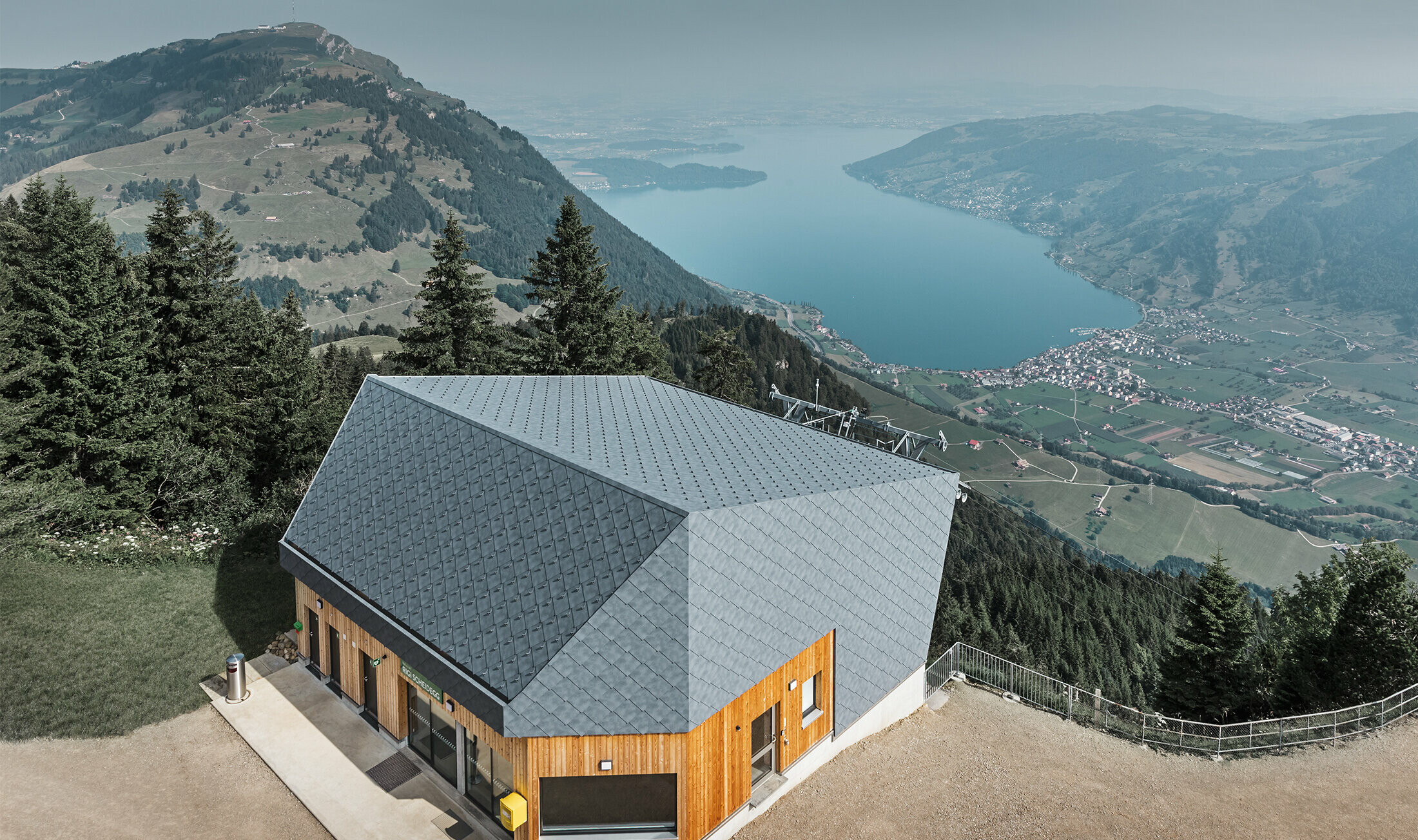 Luftfoto af bjergstationen ved Rigi Scheidegg-kabelbanen, beklædt med PREFA-vægrombe 44 × 44 i P.10 stengrå og træ.