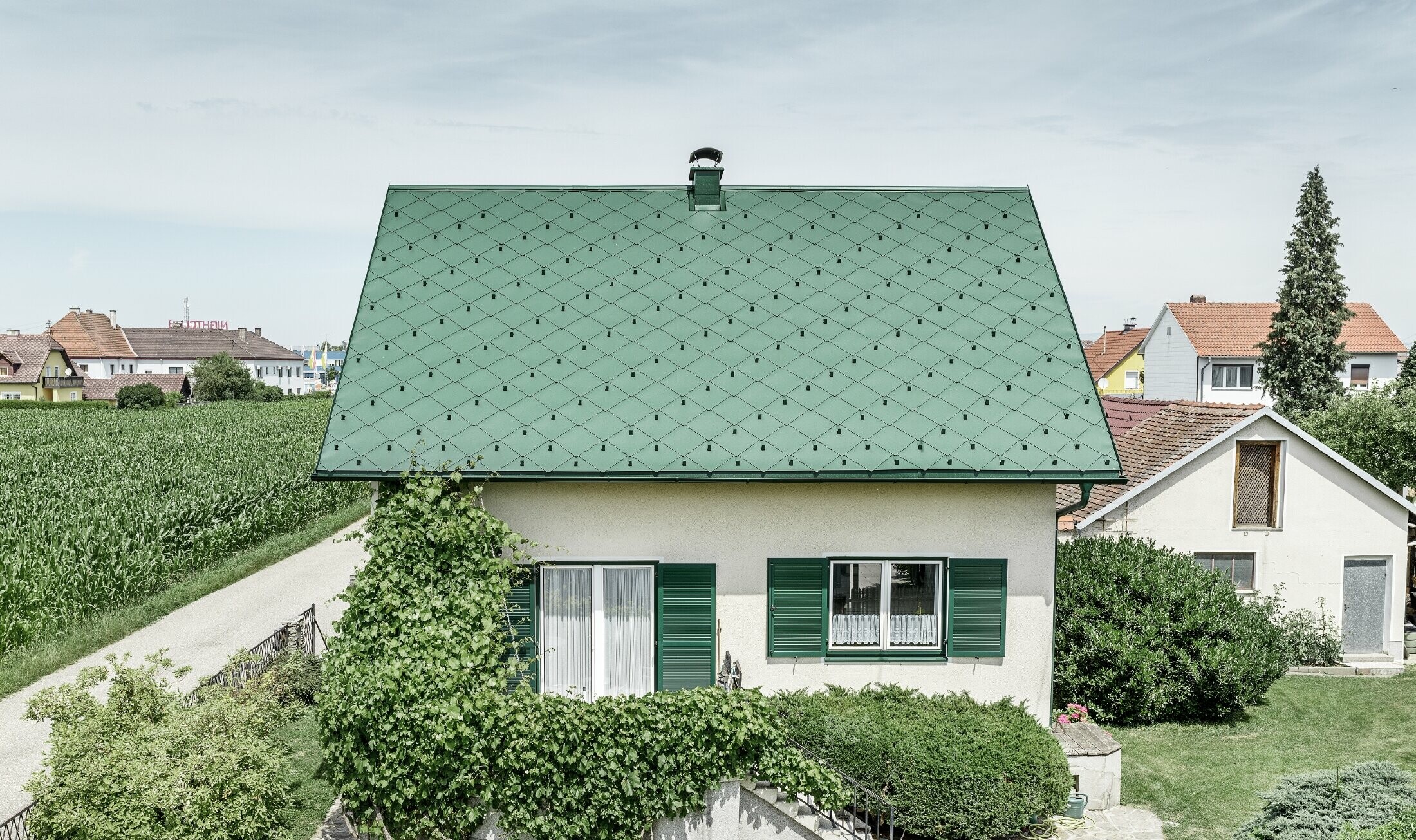 Klassisk enfamilieshus med sadeltag med en taginddækning af aluminium fra mosgrøn med grønne vinduesskodder. Taget blev beklædt med PREFA-tagrombe 44 × 44 i P.10 mosgrøn.