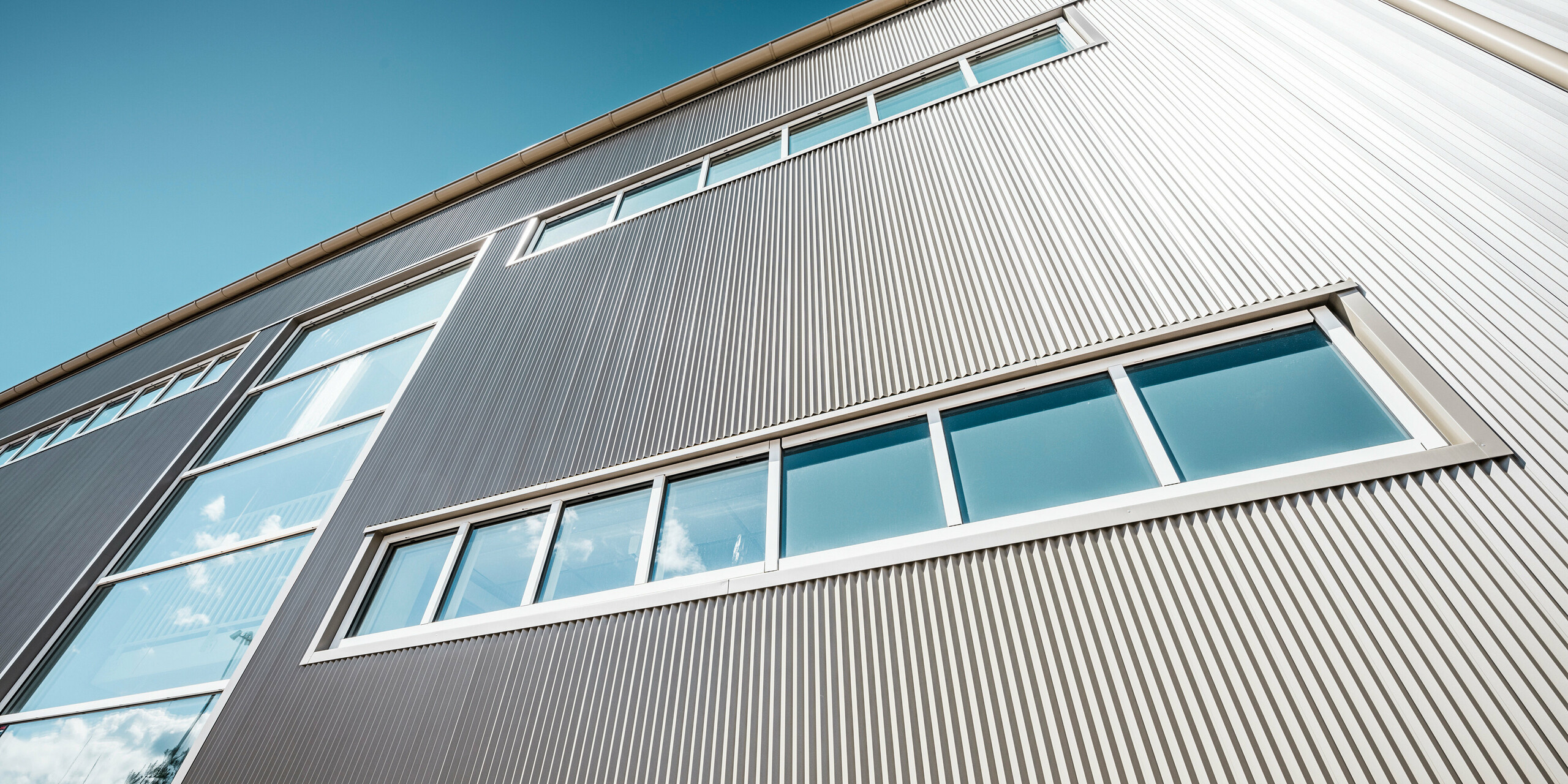 Außenansicht der Park Arena in Värnamo, Schweden, mit einer modernen PREFA Fassade in Bronze. Die Zackenprofile aus Aluminium schaffen markante Licht- und Schatteneffekte. Die eingebetteten Fenster fügen sich harmonisch in die präzise verarbeitete Fassade ein, die für Langlebigkeit, Widerstandsfähigkeit und zeitgemäßes Design steht.