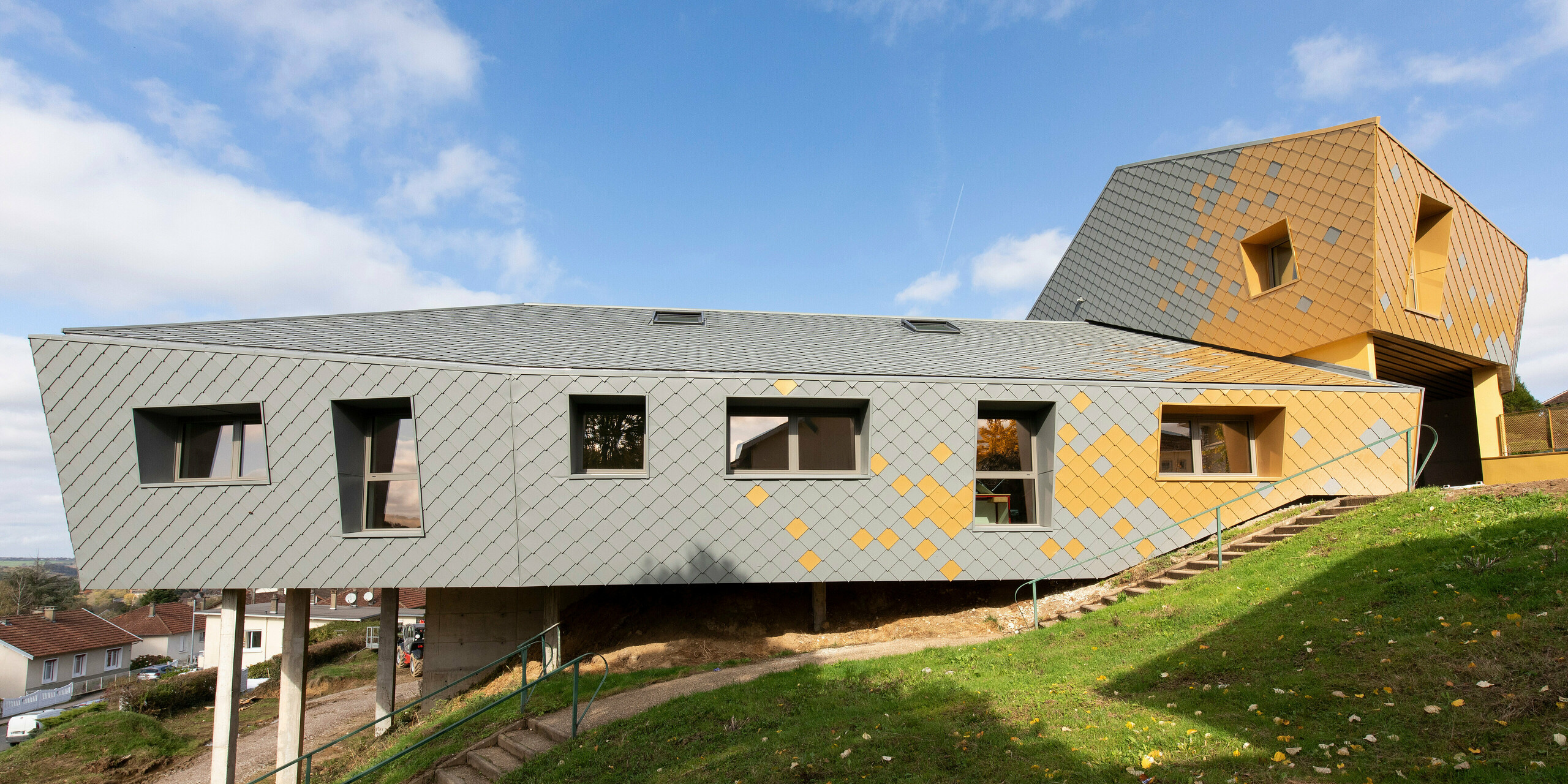 Seitliche Perspektive auf die PREFA Fassade der Grundschule Jean Peyraud in Pierre-Buffière in Hanglage