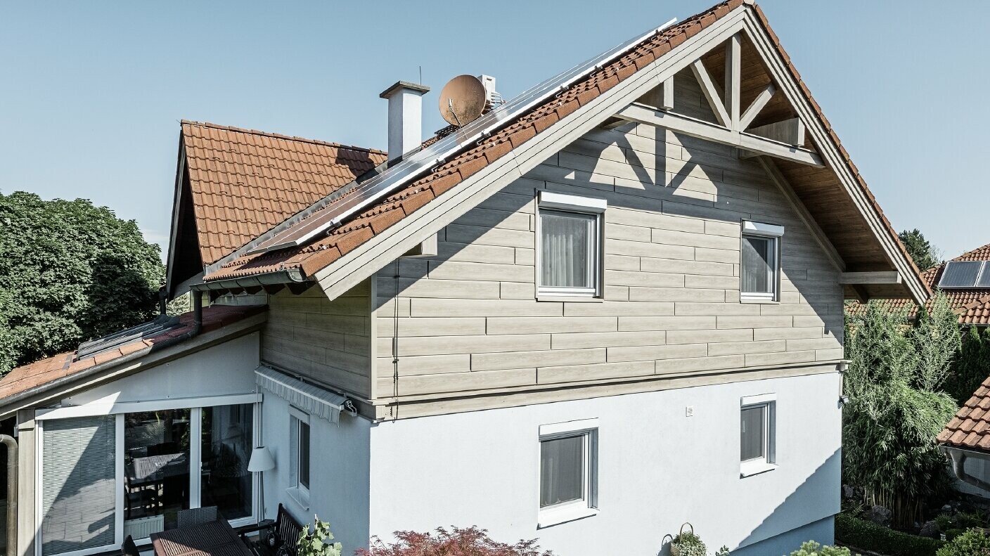 Frisk renoveret facade med bagventileret alu-facade på overetagen. Gavlen blev beklædt med sidebeklædninger med træudseende (beige-grå eg). 