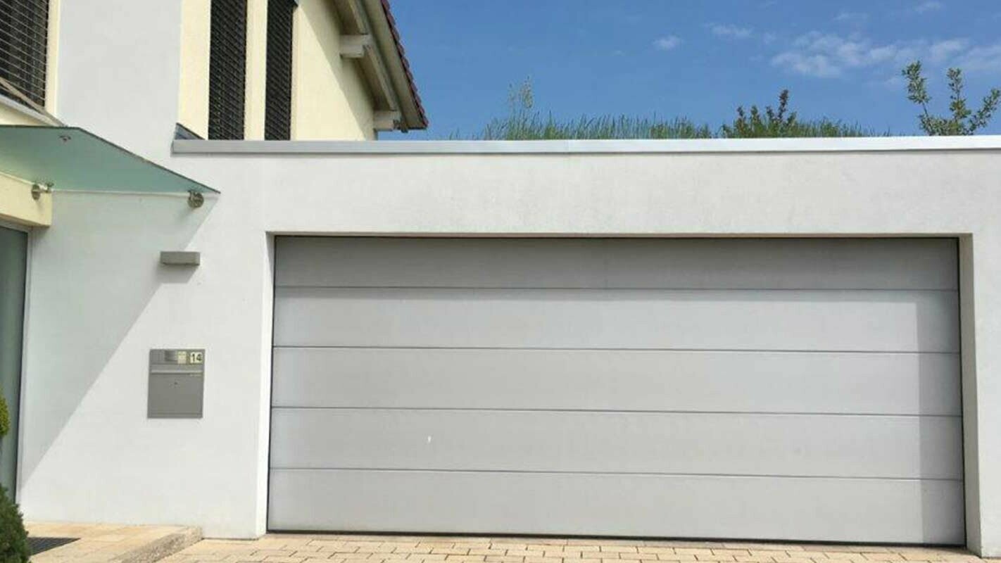 Garage før renovering med PREFA sidings i antracit, hvid facade og hvid garageport