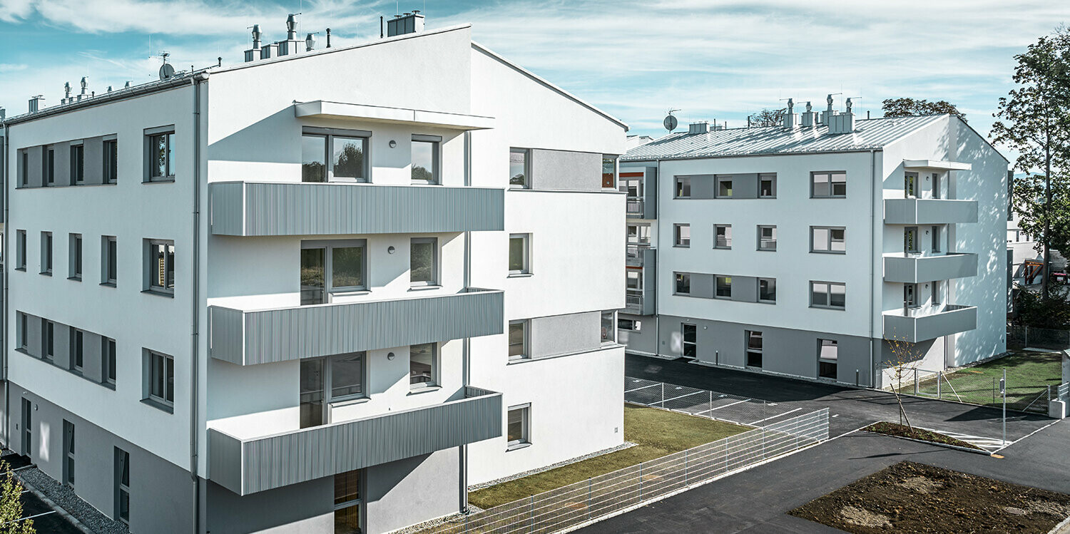 Moderne boligbyggeri med hvid facade og balkoner med takket PREFA-profil i sølvmetallic