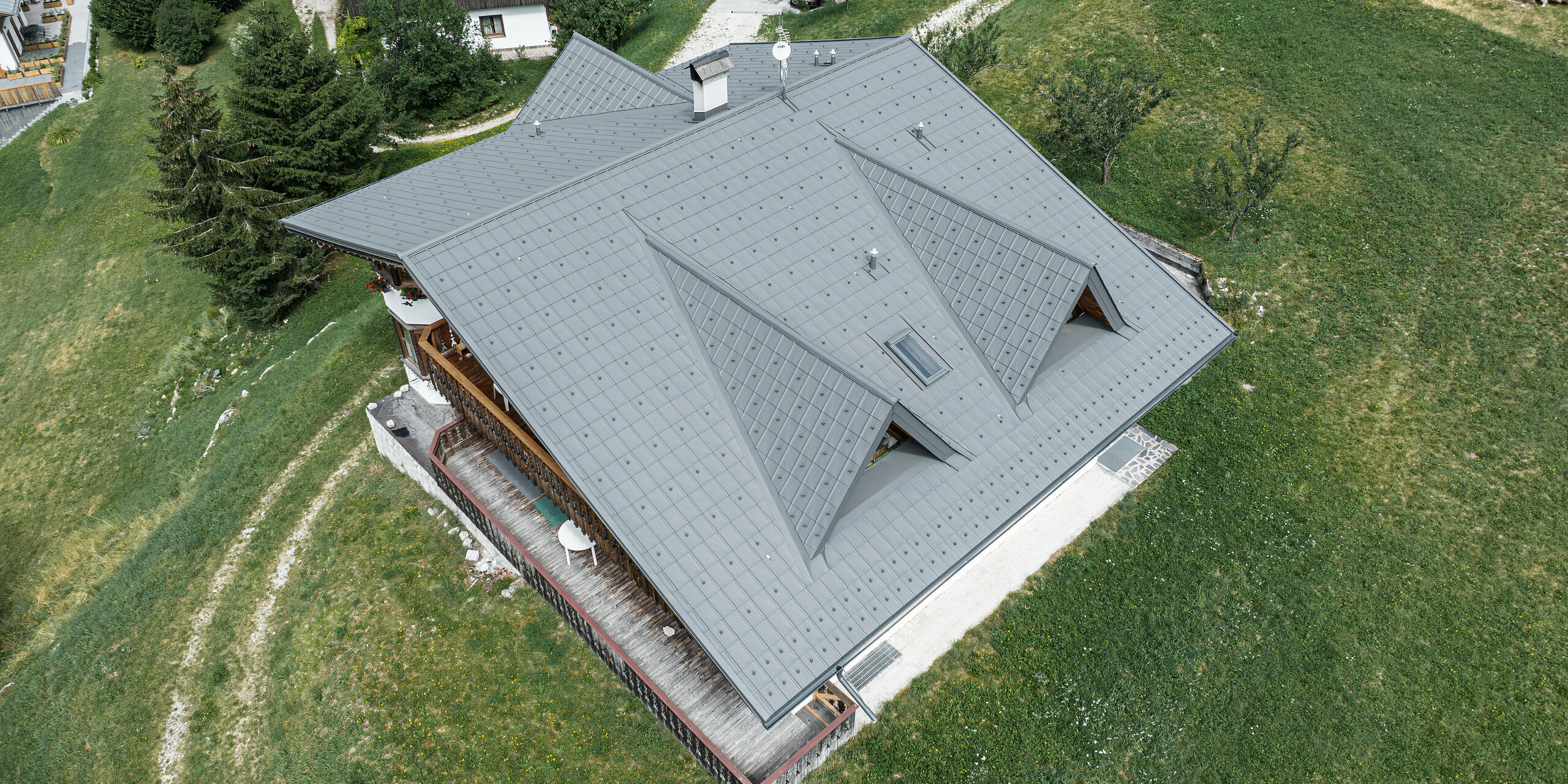 Ein Blick aus der Vogelperspektive auf das robuste Dach einer Berghütte in Italien. Das Gebäude wurde mit hochwertigen PREFA Dachplatten eingedeckt.