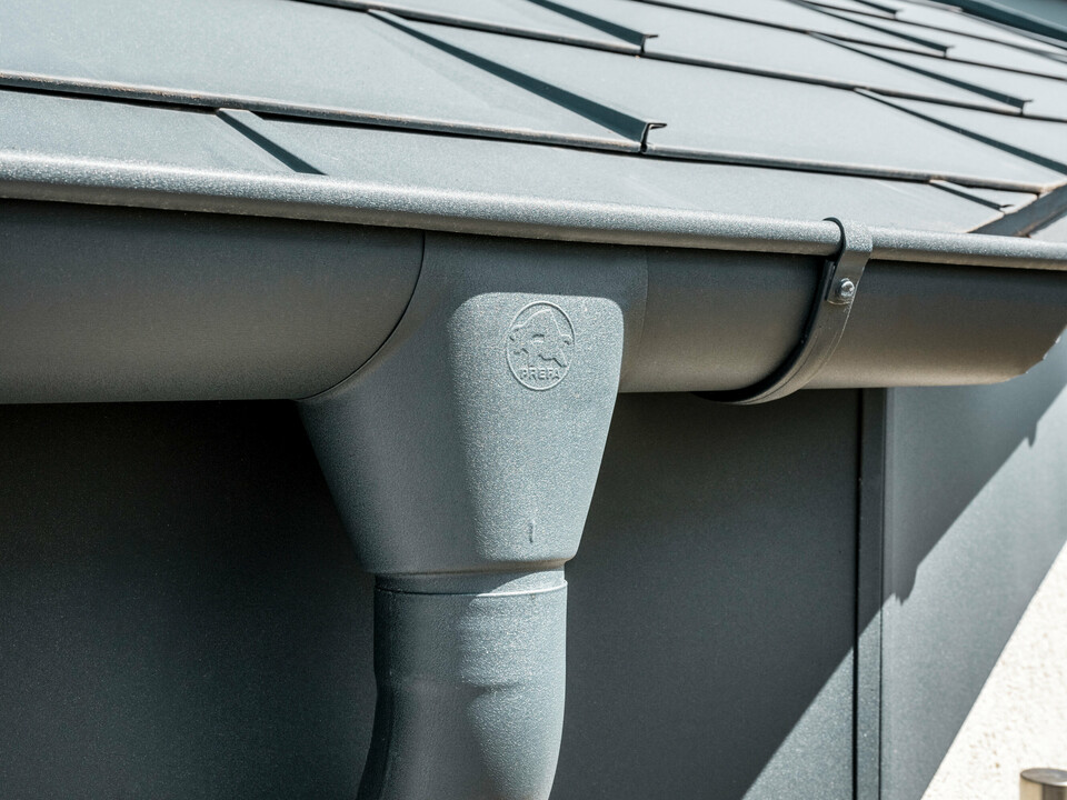 PREFA halvrund tagrende med tudstykke til rende i P.10 antracit og PREFA tagplade R.16 Enkeltfamiliehus i Newel-Besslich med PREFA Tagplade R.16 og PREFA tagafvandingssystem i antracit