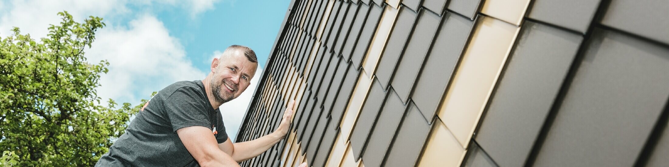 PREFA Handwerker in Ihrer Nähe an einer Fassade mit PREFA Wandrauten in Braun und Mayagold.