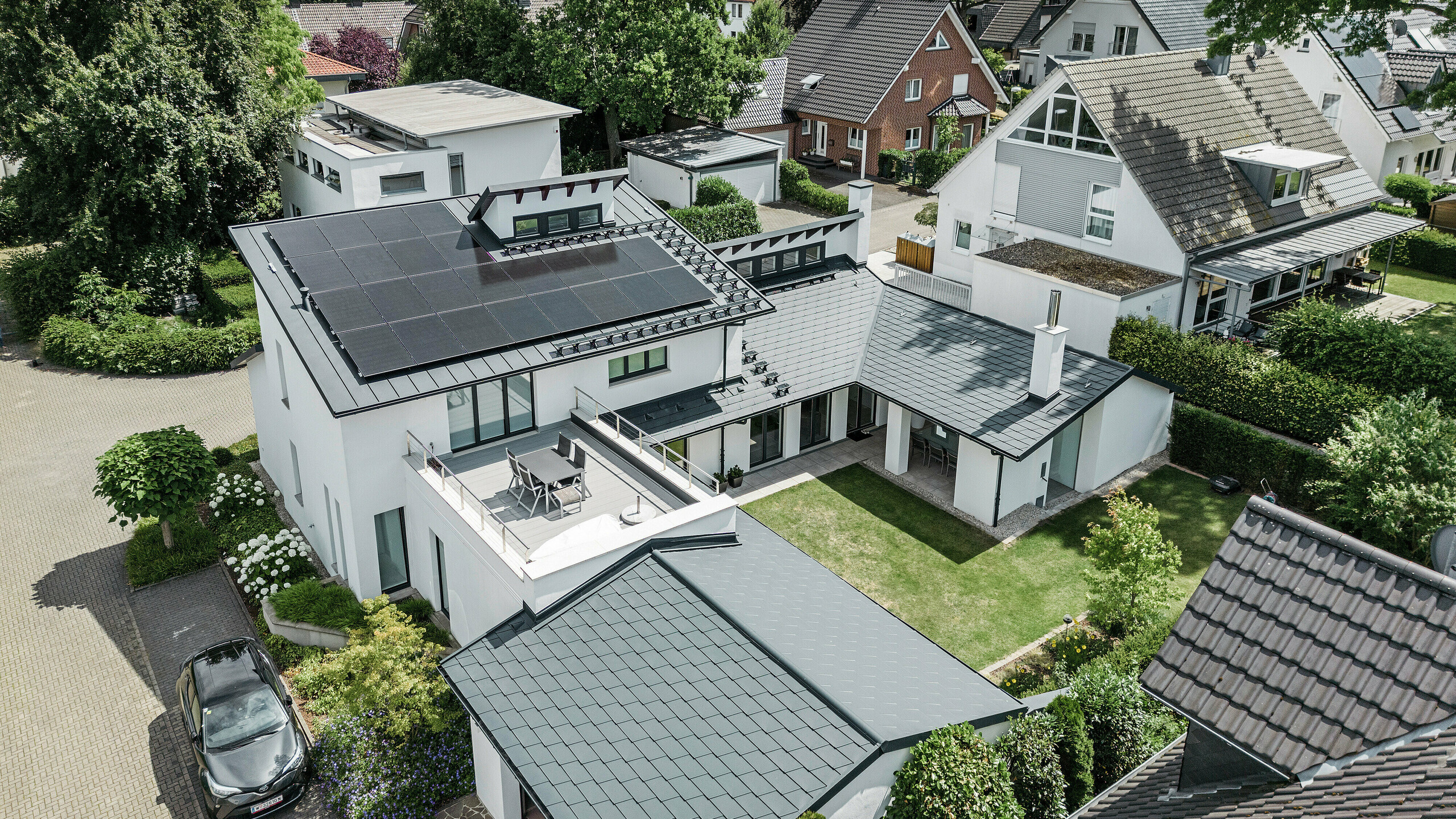 Fågelperspektiv på det enastående taklandskapet på ett enfamiljshus i Dortmund med PREFA takshingel DS.19 och PREFALZ i P.10 antracit samt en storskalig solcellsanläggning